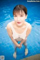 A woman in a white tank top standing in a pool.