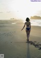 A woman in a bikini walking on the beach.