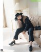 A woman sitting on a couch wearing a black hat.