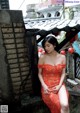 A woman in a red dress sitting on a ledge.