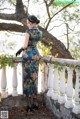 A woman in a blue and green dress standing on a balcony.