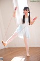 A young girl in a white dress is holding a pink skipping rope.