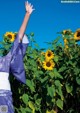 A woman in a blue kimono standing in a field of sunflowers.