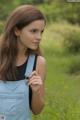 A young woman in overalls standing in a field.