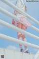 A young girl in a white shirt and pink skirt standing on a railing.