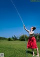 A woman in a red skirt is spraying water on her face.