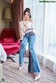 A woman in a white top and blue jeans posing for a picture.