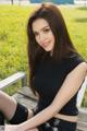 A woman sitting on a wooden bench in a park.