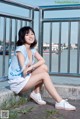 A woman sitting on a railing by the water.