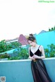 A woman in a black dress standing on a balcony.